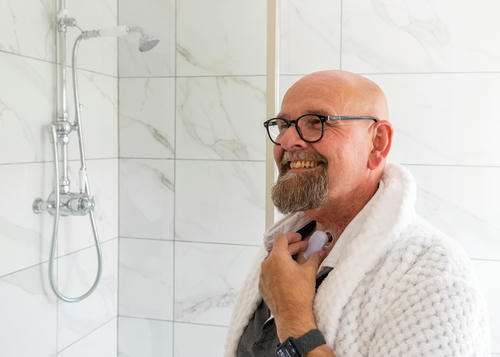 Man in shower smiling putting his Stoma protector in.